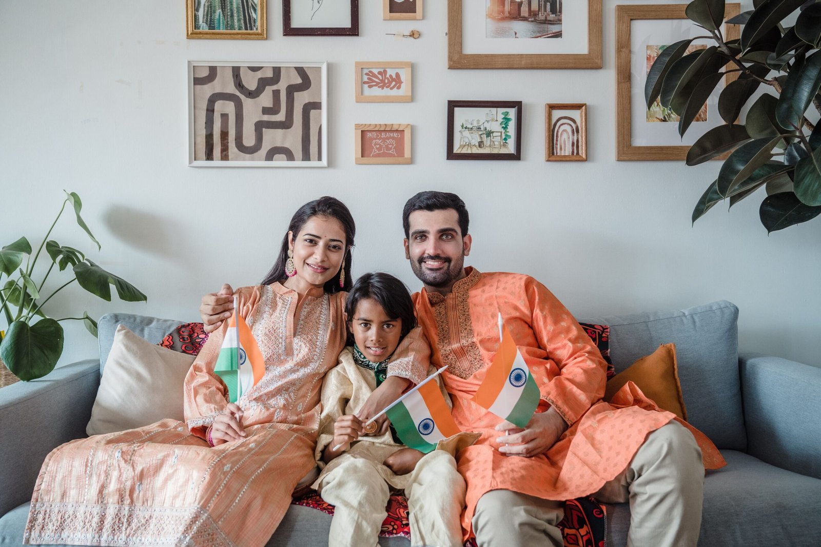 Indian family in traditional attire celebrating Independence Day with flags indoors.